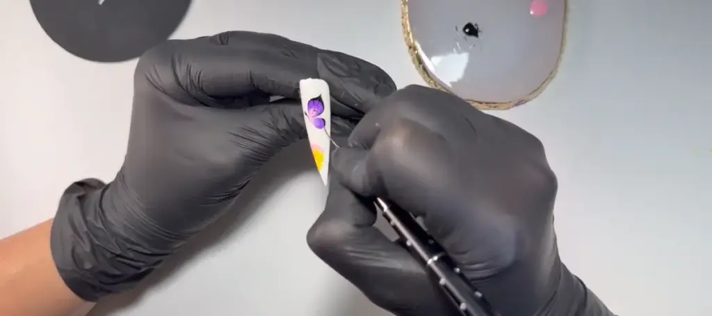 Técnico de uñas practicando decoración en acuarela